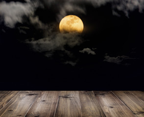halloween background. wooden table over full moon with clouds at night.
