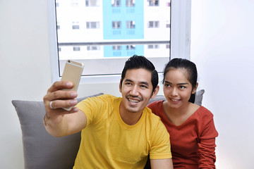 Wall Mural - Happy asian couple having fun and taking a selfie