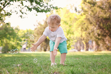 Wall Mural - Cute baby boy walking in green park on sunny day