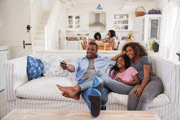 Poster - Father Sitting On Sofa Watching TV With Teenage Daughters