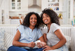 Portrait Of Mother Sitting With Teenage Daughter On Sofa
