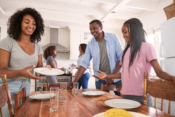 Wall Mural - Family With Teenage Daughters Laying Table For Meal In Kitchen