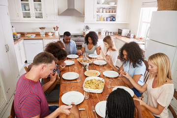 Wall Mural - Two Families Saying Grace Before Eating Meal Together