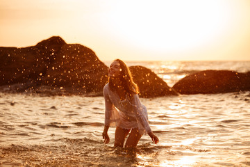 Poster - Happy brunette woman in light summer dress playing in sea