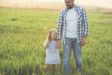 father and daughter walking in high grass field