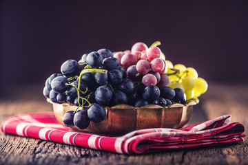 Wall Mural - Grape. Bunch of multicolored grapes in retro bowl on old oak table