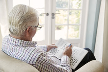 Senior Man Sitting In An Armchair Doing  Crossword, Close Up