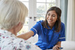 Young care nurse on home visit comforting senior woman