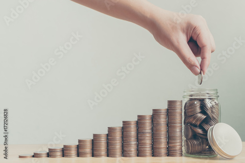 Cuadros en Lienzo Hand of male or female putting coins in jar with money stack step growing growth