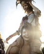 © Mint Images - Young woman at summer music festival carrying friend on her shoulders
