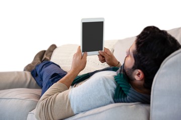 Wall Mural - Man lying on sofa while using digital tablet