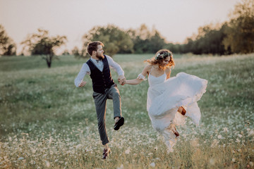 Wall Mural - Beautiful bride and groom at sunset in green nature.