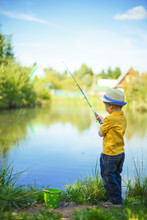 Little Boy Is Engaged In Fishing In A Pond. Child With A Dairy In His Hands.