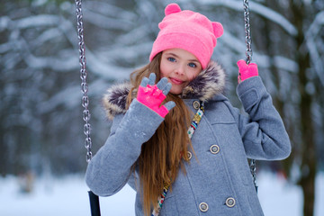 Charming little girl on swing in snowy winter