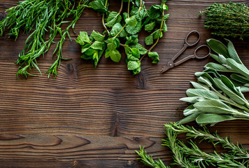 fresh herbs and greenery for spices and cooking on wooden desk background top view mock up