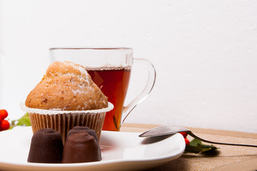 A fragrant cupcake with sweets and tea on a white background