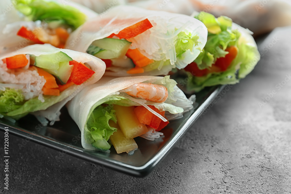 Plate with fresh spring rolls in rice paper on table