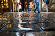 People walking on wet paving stones in rainy day in old town of Prague