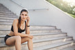 Young and confident female fitness trainer listening to upbeat music to start her everyday urban workout on a stairway to perfect body.
