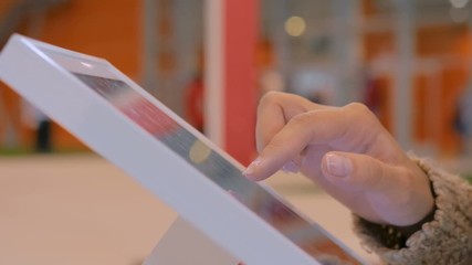Woman using interactive touchscreen display at urban exhibition - scrolling and touching. Entertainment and technology concept