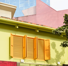 Three Orange Windows With Shutters On Yellow Wall
