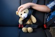Teenage boy sitting with teddy bear in the back seat of car