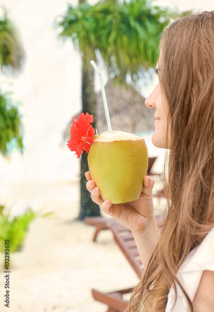 Young woman with fresh coconut cocktail at resort