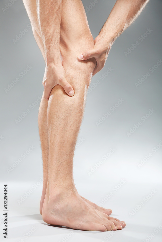 Young man suffering from pain on light background