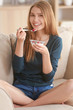 © Africa Studio - Young woman eating yogurt on sofa at home
