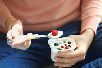 Wall Mural - Young woman eating yogurt, closeup