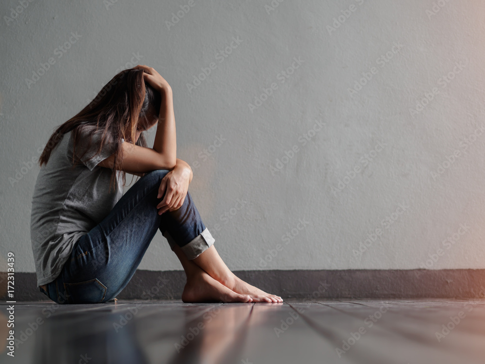 Sad woman hug her knee and cry while sitting alone in a empty room ...