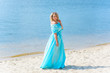 © T.Den_Team - Nice woman in blue long dress walk on a beach and relax at warm day. Tenderness plus size blonde hair lady look stylish and sweet
