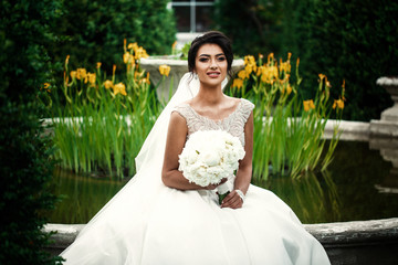 Wall Mural - Pretty bride sits on a fountain in the garden