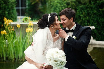 Wall Mural - Lovely bride and groom sit on a fountain in the garden