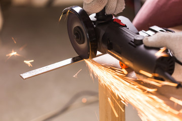 Worker Using Angle Grinder in Factory and throwing sparks.