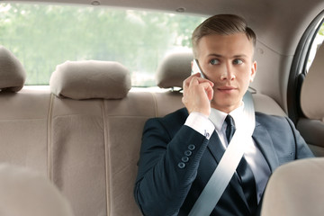 Wall Mural - Young businessman talking on phone in car