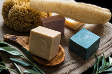 Various Colored Olive Oil Soaps And Natural Sponges On Sackcloth