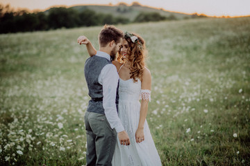 Wall Mural - Beautiful bride and groom at sunset in green nature.