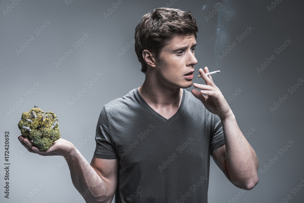 broccoli cigarette Heavy smoker showing result of nicotine harm on broccoli Stock Photo