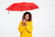 Picture Of Smiling African Woman In Raincoat Hiding Under Umbrella