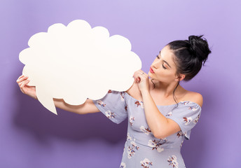 Young woman holding a speech bubble on a solid background