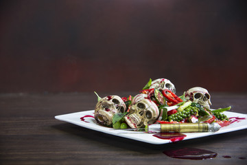 Stir-fry skulls with chili and pepper with blood on the wooden table, Halloween day food.