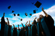© sippakorn - Group of graduates with congratulations throwing graduation hats in the air celebrating.