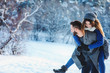 © mashiki - happy loving couple walking in snowy winter forest, spending christmas vacation together. Outdoor seasonal activities. Lifestyle capture.
