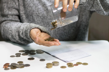 Wall Mural - The woman poured a coins from the jar into her hand, Coins fall into the hands of young women. Concept of money saving and financial. Selective focus.