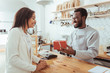 © zinkevych - Smiling barista giving his customer a box with order