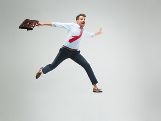 Wall Mural - Businessman running with a briefcase, isolated on gray background