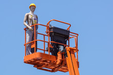 Hydraulic Mobile Construction Platform Elevated Towards A Blue Sky With False Construction Workers . Dummy Man