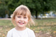 © Gribanov - Portrait of a small laughing blond girl in nature with blurred background