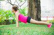 © Nusara - Asian woman warm up to exercise by body weight pushup on green lawns in park for health